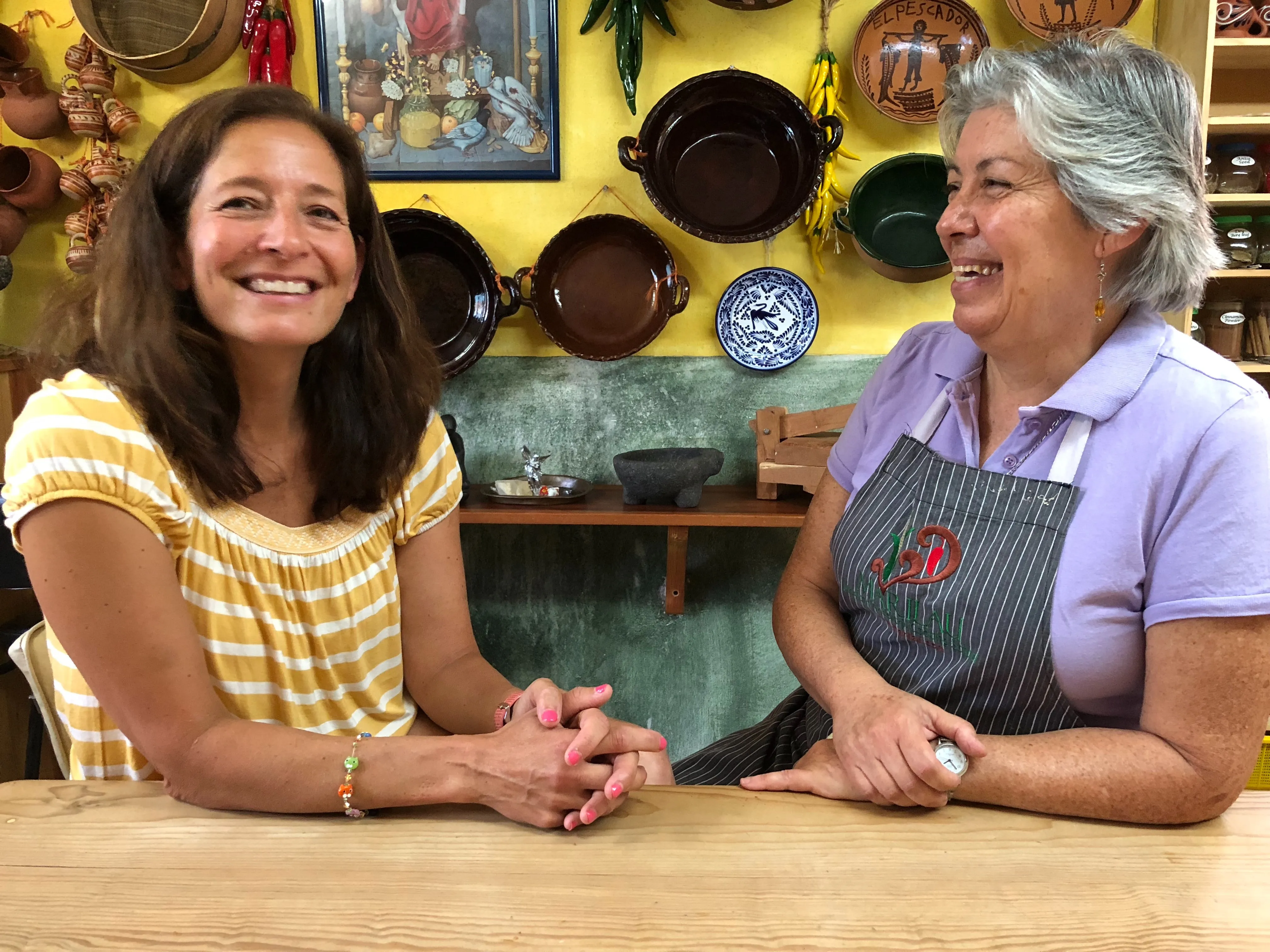 A student and Marilau laughing together at the class table