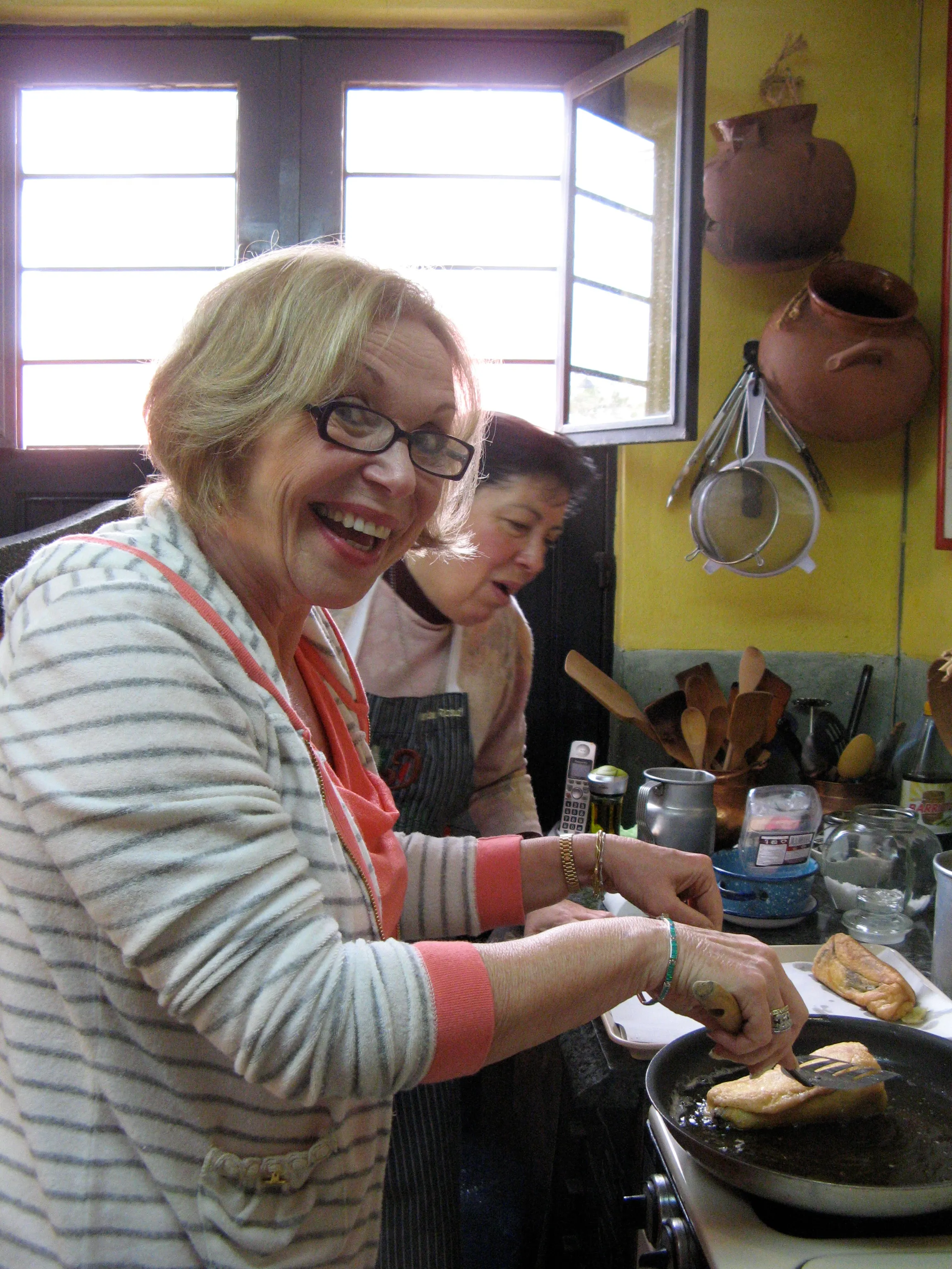 A student frying chiles rellenos at the stove with Marilau
