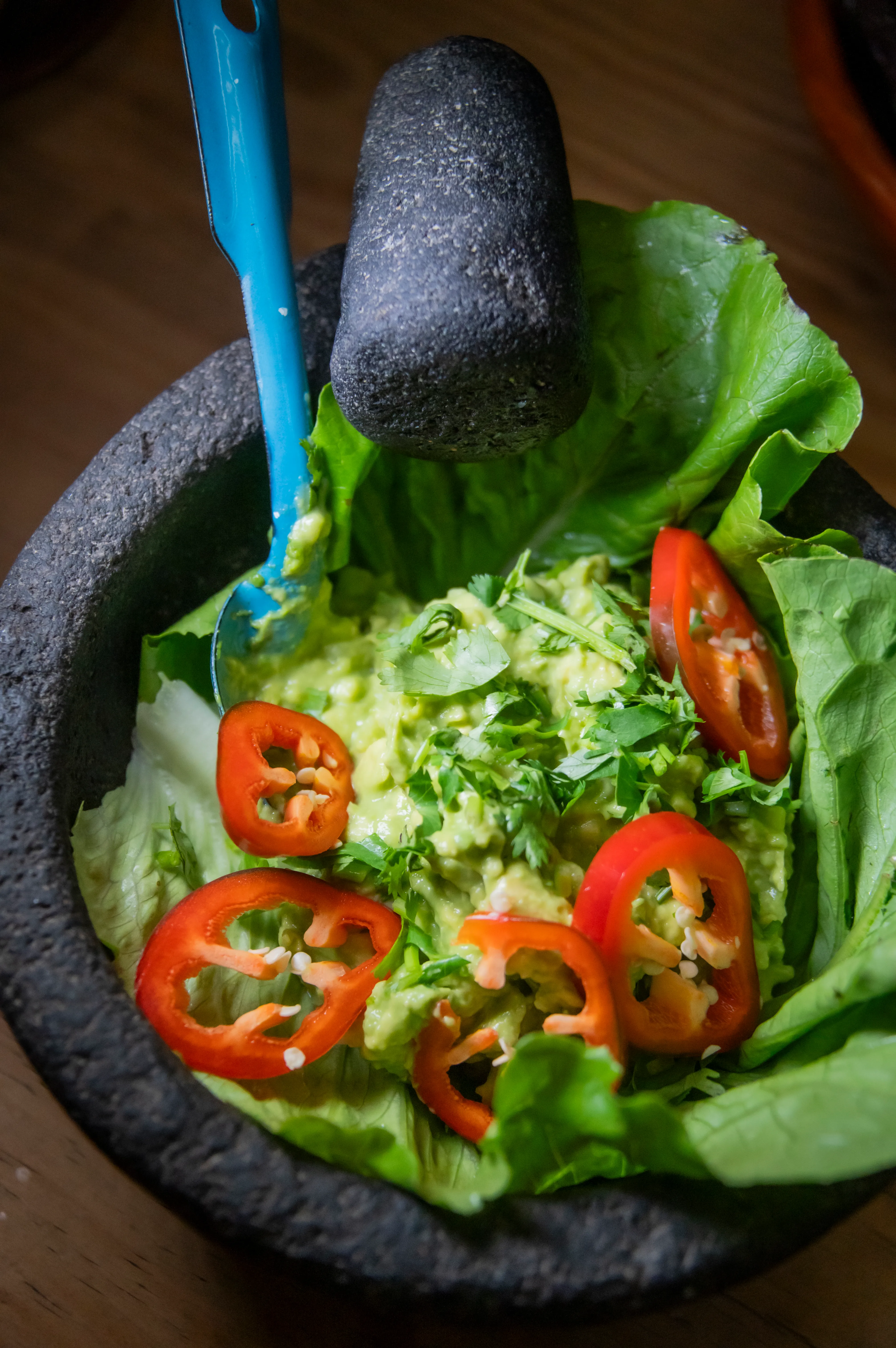 Guacamole garnished with chile rings in a stone molcajete