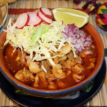 Pozole rojo topped with cabbage, radish and lime