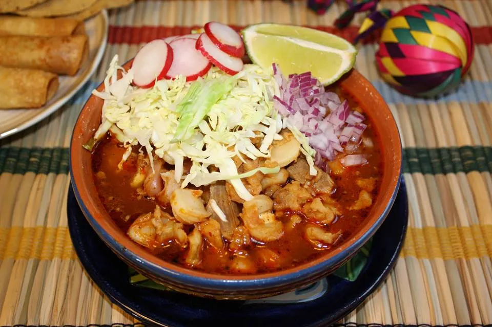 Pozole rojo topped with cabbage, radish, onion and lime, with tostadas