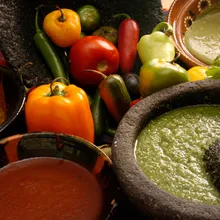 Salsas in molcajetes surrounded by fresh chiles