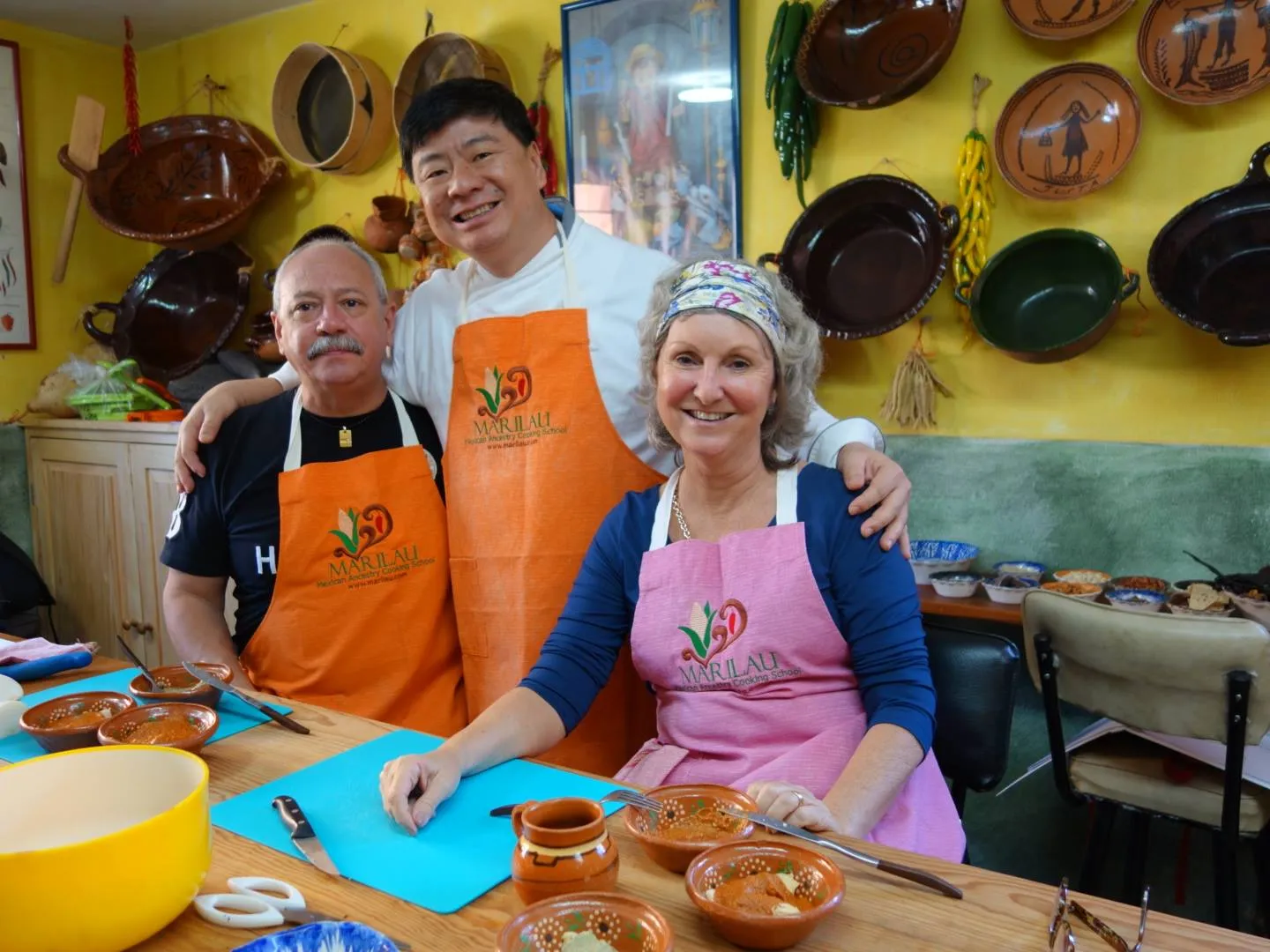 Three students in Marilau aprons at the class table