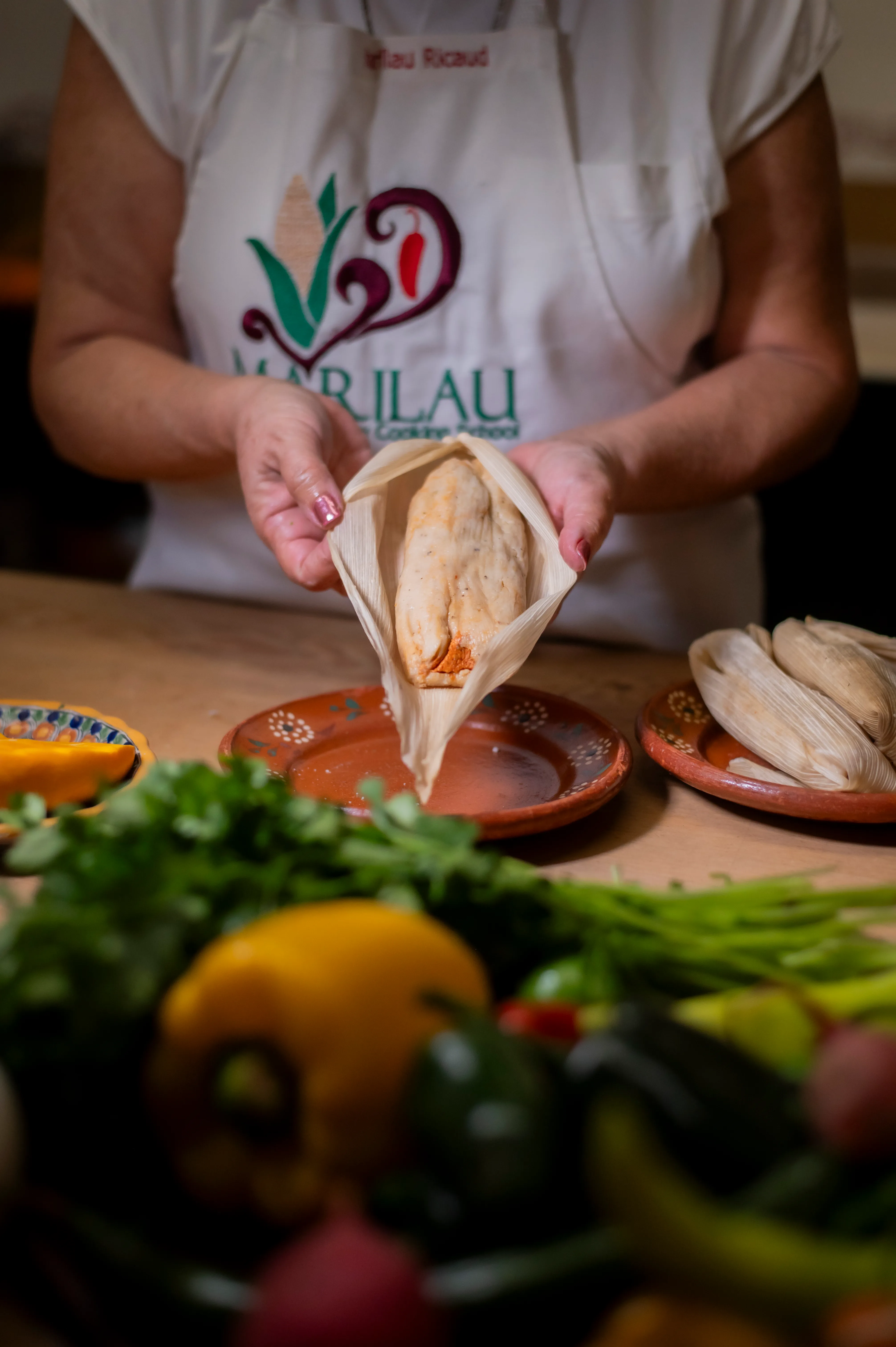 Marilau’s hands opening a freshly steamed tamal in its corn husk