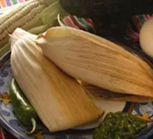 Tamales in corn husks on a talavera plate